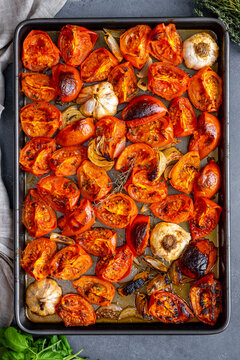 Tomatoes, onion and garlic roasted on a baking sheet.