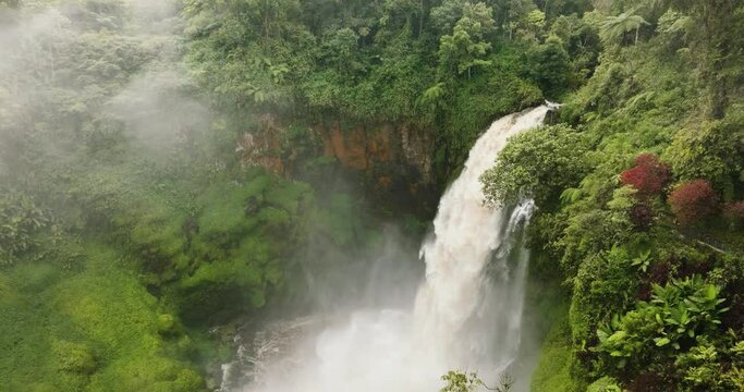 Aerial drone of waterfall in a mountain gorge in the jungle. Telun Berasap Falls. Sumatra, Jambi, Indonesia.