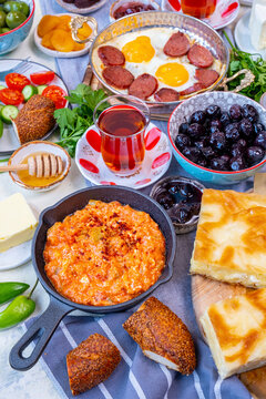 Turkish breakfast with menemen, eggs and sujuk, olives, jams, simit, borek, butter, honey, salad and Turkish tea.