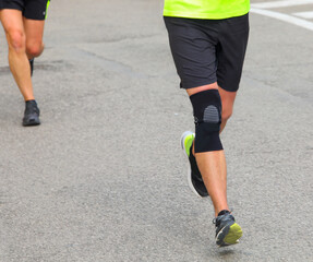 Fototapeta na wymiar runner with kneegiera runs during the running race in the paved road