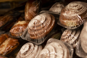 Fresh sweet snail buns with powdered sugar in a package on a shelf in a store. Side view. Close-up.