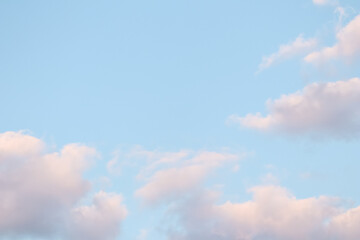 Blue sky background with pale pink clouds at sunset