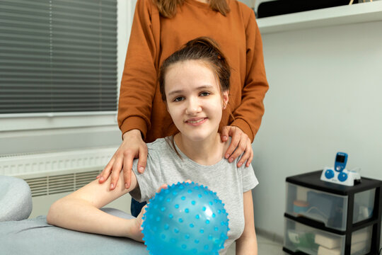 Portrait Of Pretty Smiling Teenage Girl With Cerebral Palsy With Mother Hugging Girl's Shoulders.Caring Loving Parent, Rehabilitation. Balance And Posture Maintenance, Parental Support. Horizontal