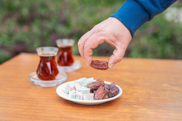 Dry Dates in a bowl and tea in armudu glass. Ramadan kareem.  Outdoor  background.