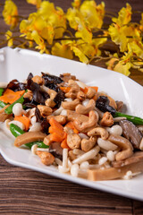 stir fried white shimeji mushroom with scallop black fungus cashew nut deep fried yam bean curd and mixed colourful vegetables on wood table asian Chinese vegan halal food banquet menu for restaurant
