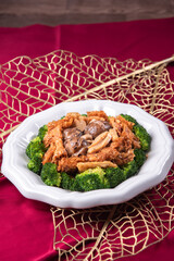 braised assorted dried seafood sea cucumber mushroom bean curd skin and broccoli mixed vegetables in sauce casserole on wood table asian chinese halal food banquet menu for restaurant