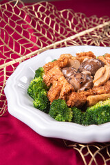 braised assorted dried seafood sea cucumber mushroom bean curd skin and broccoli mixed vegetables in sauce casserole on wood table asian chinese halal food banquet menu for restaurant