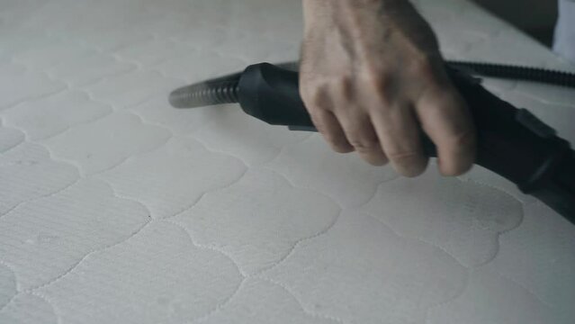 Close-up. Cleaning the mattress with a steam cleaner. Heat treatment and cleaning from dirt and insects of bedding.