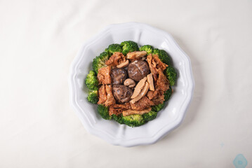 braised assorted dried seafood sea cucumber mushroom bean curd skin and broccoli mixed vegetables in sauce casserole on wood table asian chinese halal food banquet menu for restaurant