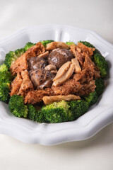 braised assorted dried seafood sea cucumber mushroom bean curd skin and broccoli mixed vegetables in sauce casserole on wood table asian chinese halal food banquet menu for restaurant