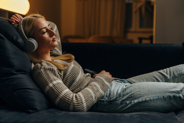 A beautiful blond woman is resting on the sofa