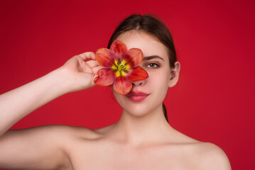 Obraz na płótnie Canvas Beauty girl with tulip near face. Beautiful sensual woman hold tulips, studio portrait on red background.