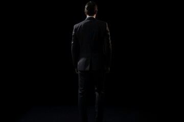 Business Concept. Isolated Businessman in Black Suit on black Background