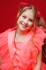 portrait of a beautiful teenage girl with ponytails in a pink elegant dress. 
