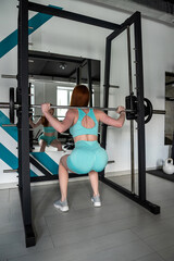 Fototapeta na wymiar Young red-hair caucasian trainer doing exercise with barbell and heavy discs