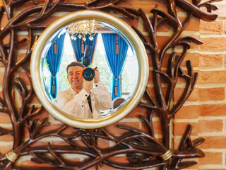 a man with a camera takes his photo in the reflection in the mirror. 
