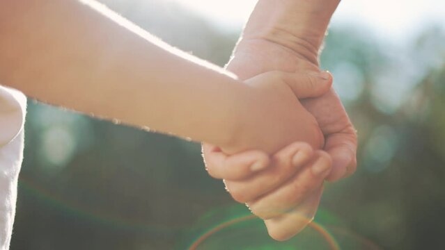 happy family father and daughter hold hands close up. Dad and baby girl hands together at sunset. Father Day. Dad and daughter are holding hands. A father extended a helping hand to his daughter child