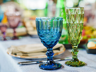 glasses of colored glass on a table with a blue tablecloth. 