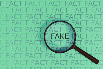 Fake News concept with words 'fact' in row and single word  'fake' highlighted by magnifying glass...