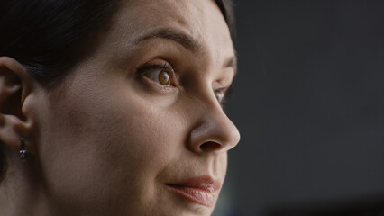 Obraz premium Close up face portrait of charming caucasian woman with serious and focused look. Confident female worker stares away, moves eyes, poses on camera. Woman stands in studio or office on grey background.