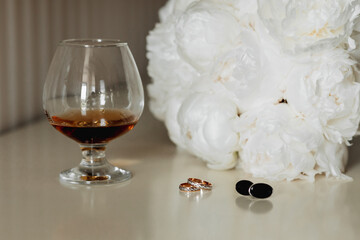 Accessories for the groom's wedding. A goblet with a drink, a white bouquet for the bride, gold...