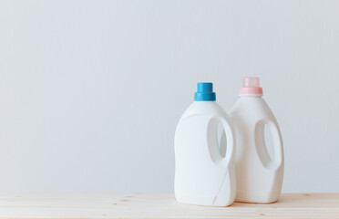 Washing gel liquid laundry detergent and fabric softener on a wooden table against a light white background with copy space.