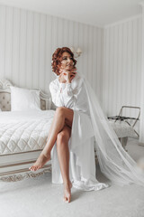 fashion shot, beautiful woman in a dressing gown. Fashion, glamor concept. The morning of the bride, the bride in a dressing gown keeps sitting on the bed and poses for the photographer