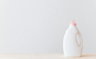 Washing gel liquid laundry detergent or fabric softener on a wooden table against a light white...
