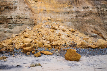 boulders on the beach from a broken cliff