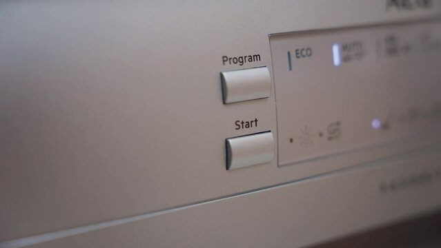 Man Hand Press Start Button on Dishwasher. Starting Dishwasher. Selecting Program On Dishwasher Macro Close up.