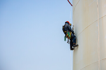 Male worker rope access inspection of thickness storage tank