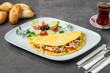Omelet with cheese, mushrooms and vegetables on a white porcelain plate