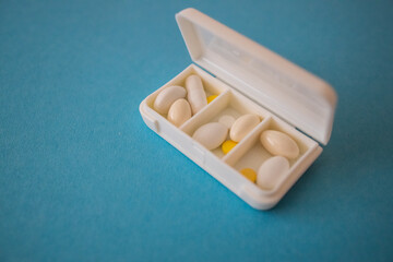 different capsules lie in a white open pill box on a blue background. View from above - 591758515
