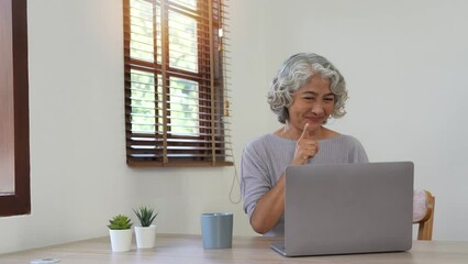 Cheerful elderly lady staying in touch with her friends or family via video connection, video call