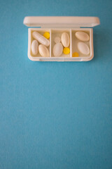 different capsules lie in a white open pill box on a blue background. View from above - 591758542