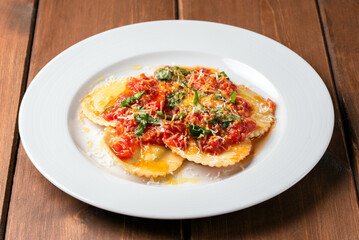 Piatto di deliziosi ravioli al pomodoro e basilico con una spolverata di parmigiano, cibo italiano 