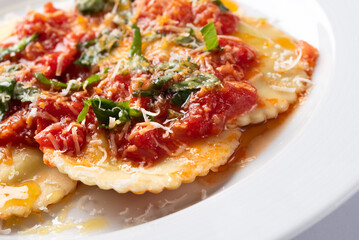 Piatto di deliziosi ravioli al pomodoro e basilico con una spolverata di parmigiano, cibo italiano 