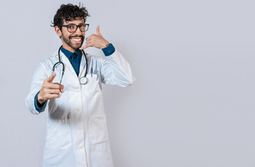 Young doctor making call gesture isolated. Smiling doctor making call gesture and pointing at the camera.