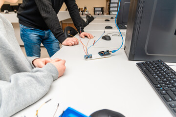 Teacher helping his teen student with diy robot on stem education class.Student In After School Computer Coding Class Building And Learning To Program Robot Vehicle.Arduino Ultrasonic installation.