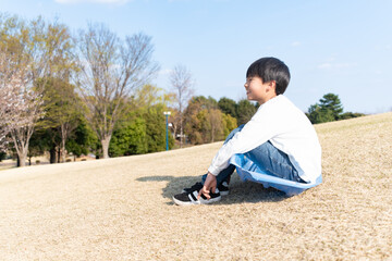 公園の芝生に座る笑顔の男の子