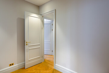 empty real estate apartment interior, corner frame on open door, white walls, parquet