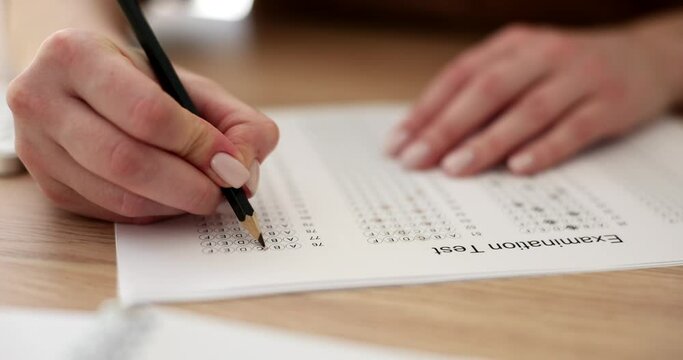 Female student highlights correct answer on paper of examination test in college. Woman checks knowledge for past academic year slow motion