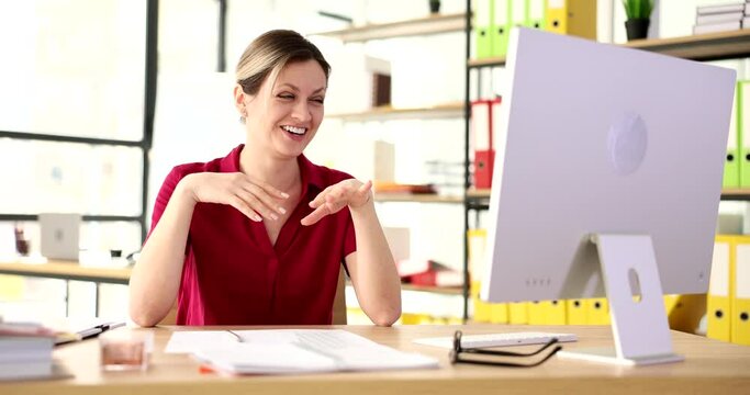 Cheerful female worker waves hands refusing to listen to funny joke. Woman bursts out laughing at workplace near computer in office slow motion