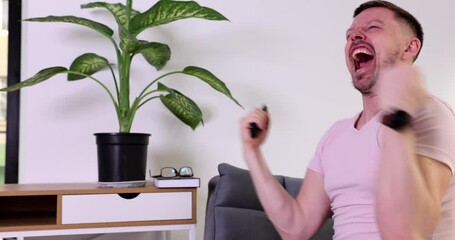 Excited man roots for favorite team watching soccer game. Emotional male person with remote control in hand feels happy for goal on Championship