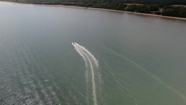 Powerboat Speeding And Leaving Wake On The Calshot Spit In Calshot, UK. aerial tilt-down