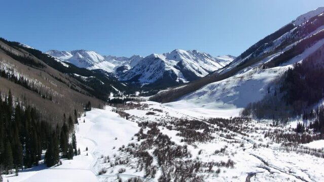 Bluebird sunny day spring winter Colorado beautiful mountain views and peaceful stream Ashcroft Maroon Bells Aspen Colorado iconic scenery aerial up motion