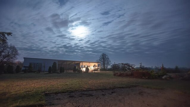 The moonlight shining through a nighttime cloudscape time lapse above a home