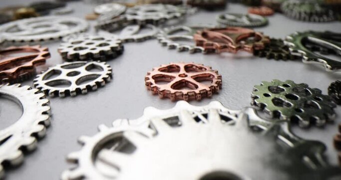 Gears and cog symbols of various sizes and colors scattered on grey surface of table. Brain function and intelligence with thinking or solution camera moves
