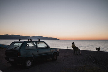 Fototapeta na wymiar anziano sulla spiaggia al tramonto con macchina