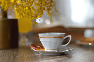Cup of tea, plates with cookies, glass of orange juice, books, reading glasses, bowl of fruit and candles on the table. Selective focus.